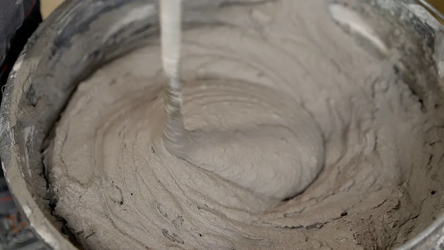 Рабочий смешивает раствор в ведре